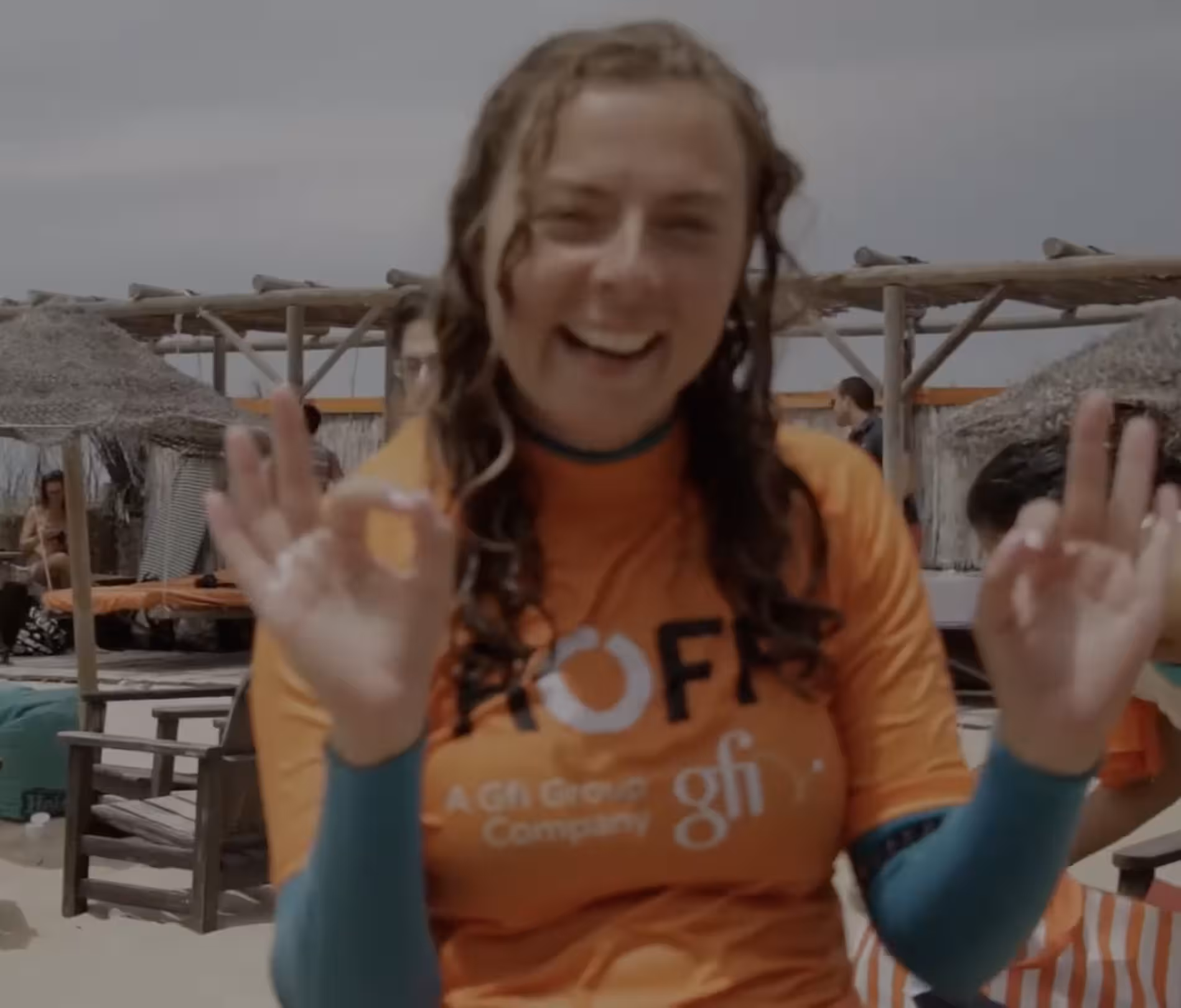Girl smiling and signalling OK after a surf lesson for a team building event.