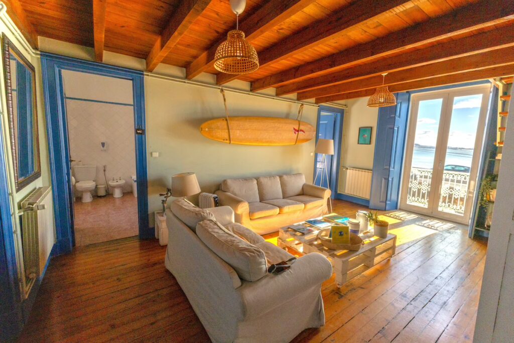 Spacious living room at the Surf Lisbon Surf House featuring ocean views, wooden ceilings and a relaxing atmosphere.